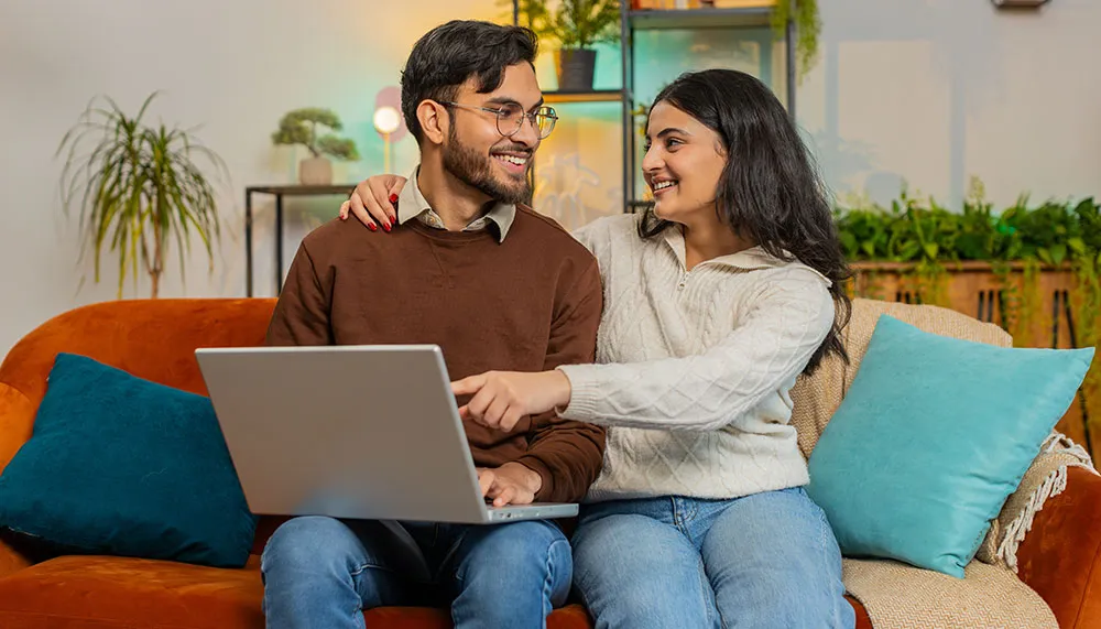 Una pareja sonriendo mientras usa una computadora.